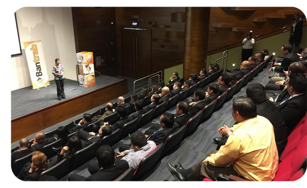 Bárbara Padilla impartiendo una conferencia en un auditorio lleno de asistentes, compartiendo estrategias sobre resiliencia y motivación.