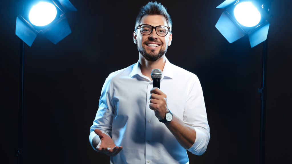 Hombre dando una charla motivacional a un grupo de personas que participan activamente levantando la mano.