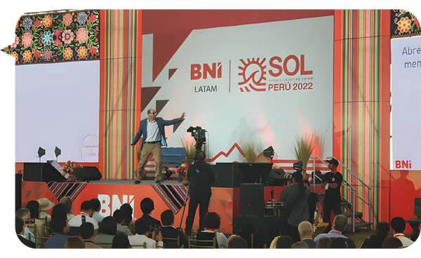 Javier Benítez Campos en el escenario durante el evento BNI LATAM SOL Perú 2022, interactuando con una audiencia comprometida.