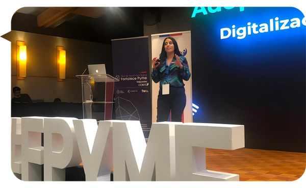 Jennifer Fernández Quinlan en un evento para pymes, hablando sobre digitalización y tecnología, con un escenario decorado con letras grandes que forman "PYME".