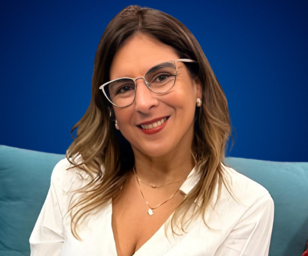 Vivianne Verschae, conferencista internacional en liderazgo consciente y transformación emocional, en retrato profesional con fondo azul.