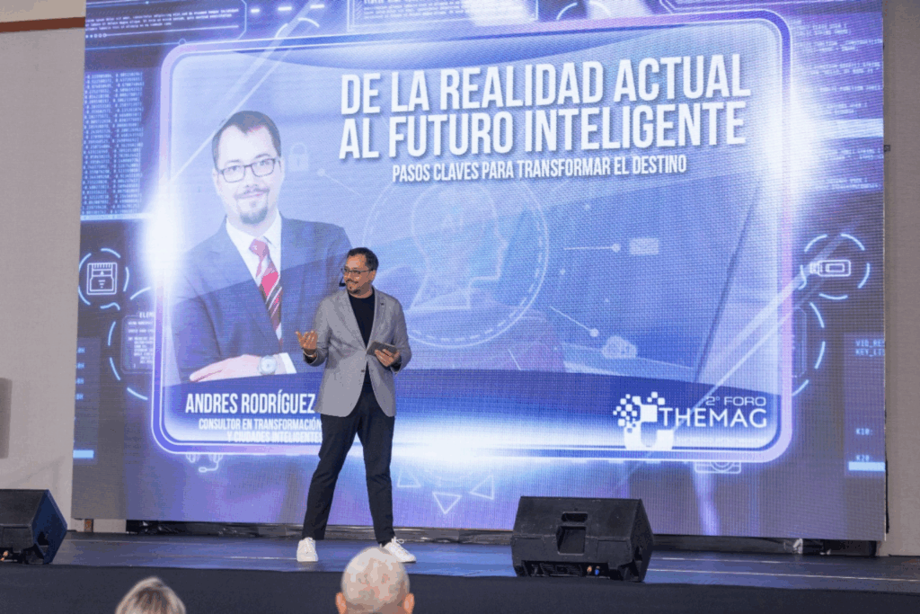 Andrés Conde en el escenario del Foro THEMAG, hablando sobre transformación digital frente a una pantalla que dice “De la realidad actual al futuro inteligente”.