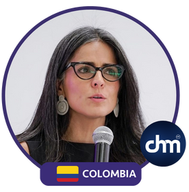 Claudia Palacios hablando como conferencista y moderadora, sosteniendo micrófono.