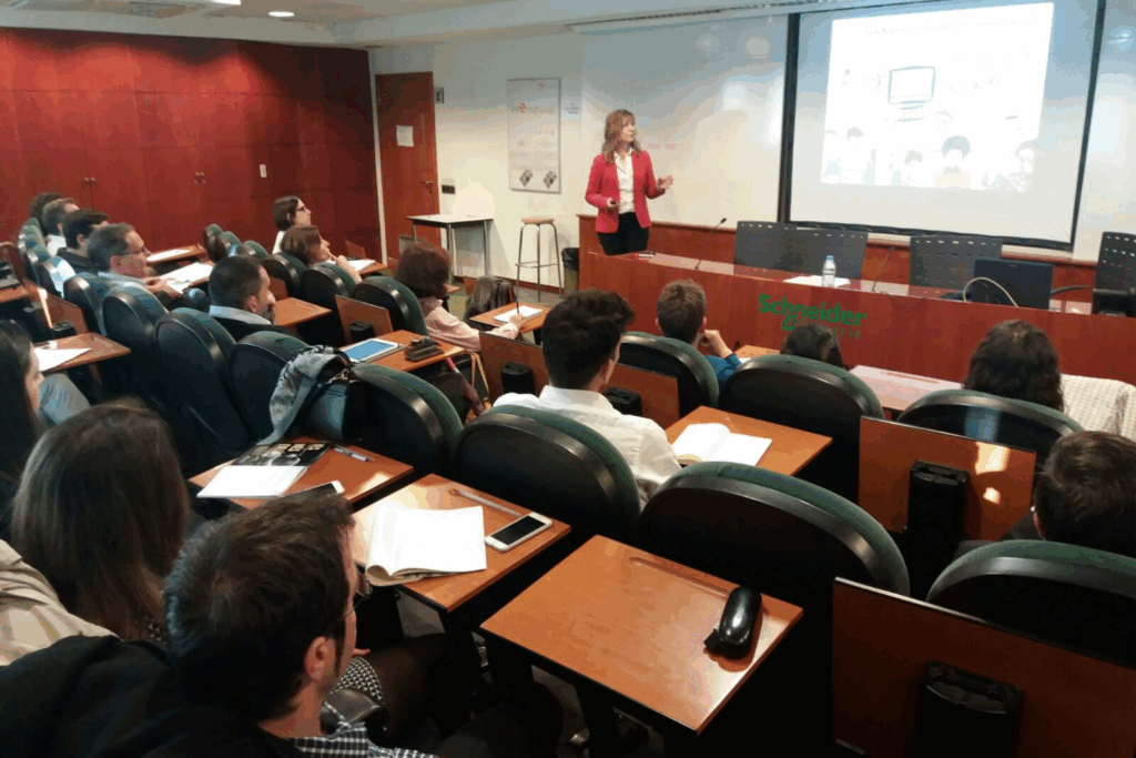 Celia Hil imparte conferencia sobre empleabilidad y talento senior en un aula universitaria con profesionales y estudiantes de diversas edades.