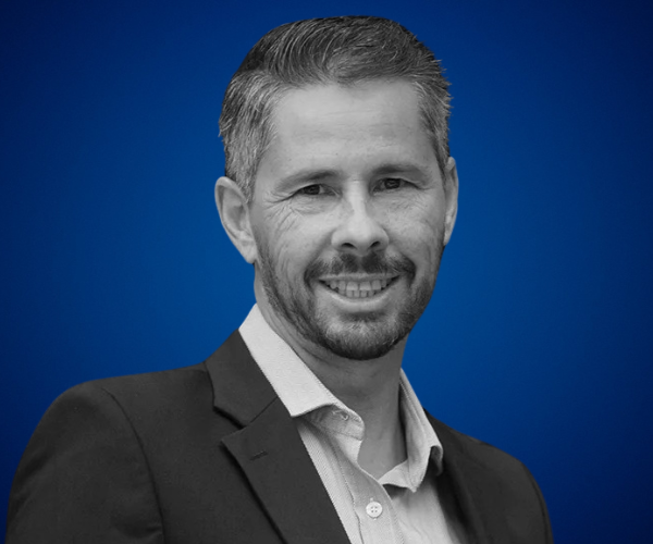 Retrato profesional de José Miguel Sánchez, psicólogo especialista en alto rendimiento, sobre fondo azul.