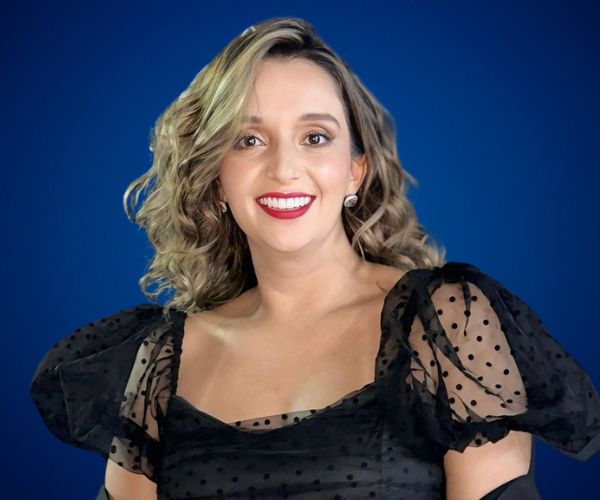 María Luisa Torres Pulido, conferencista internacional, sonriendo frente a fondo azul, experta en empoderamiento femenino y liderazgo.