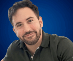 Nicolás Pasquali sonriendo, con camisa oscura, frente a fondo azul institucional de Charlas Motivacionales Latinoamérica.
