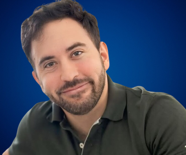 Nicolás Pasquali sonriendo, con camisa oscura, frente a fondo azul institucional de Charlas Motivacionales Latinoamérica.