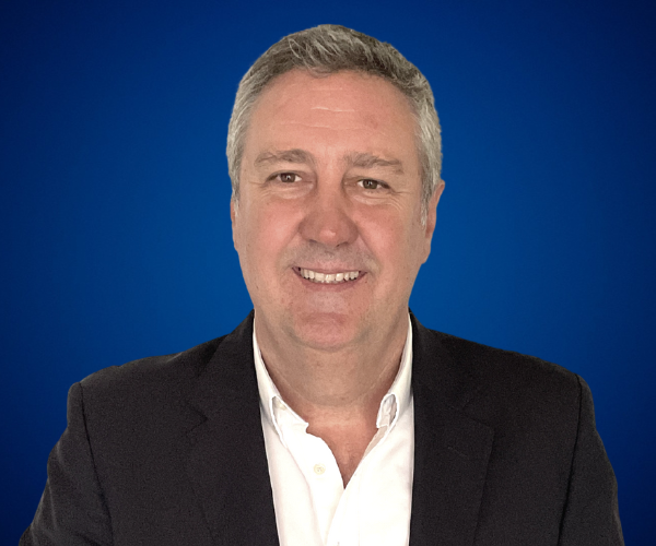 Raúl Castro, conferencista internacional experto en liderazgo y transformación cultural, sonriente con fondo azul.