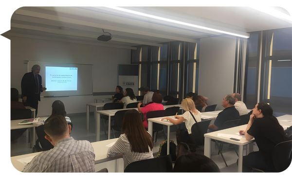 Roberto Alejandro Llauró dictando una conferencia frente a un grupo de personas en una sala de capacitación moderna.