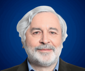 Retrato profesional de Roberto Alejandro Llauró, conferencista senior con cabello canoso, barba blanca y fondo azul.