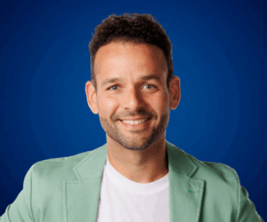 Sebastián Lora sonriendo con chaqueta verde sobre fondo azul