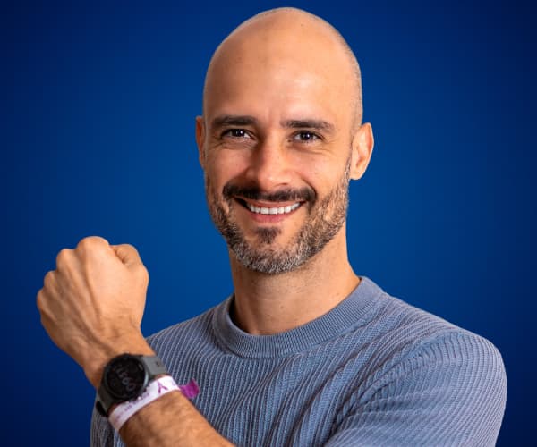 Felipe Corrales mostrando su reloj con actitud positiva y fondo azul