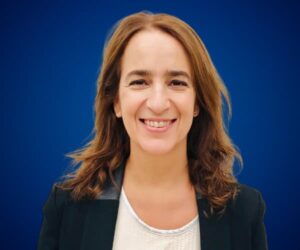 Retrato profesional de Fernanda Kersman sonriendo, con fondo azul.