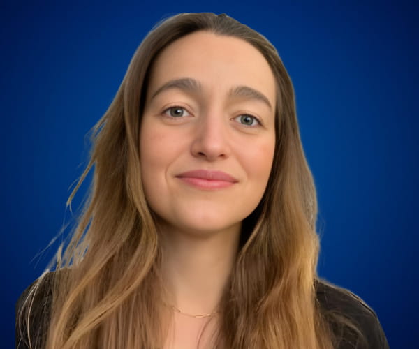 Fotografía de Francisca Deves con fondo azul, luciendo una expresión serena y profesional en un retrato de primer plano.