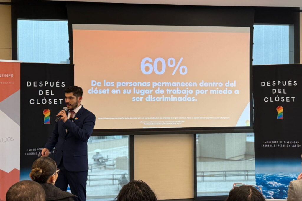 Fotografía de Edgar Dojaque impartiendo una conferencia sobre diversidad e inclusión laboral LGBTQ+, con una diapositiva que señala que el 60% de las personas permanece en el clóset en su trabajo por miedo a ser discriminadas.