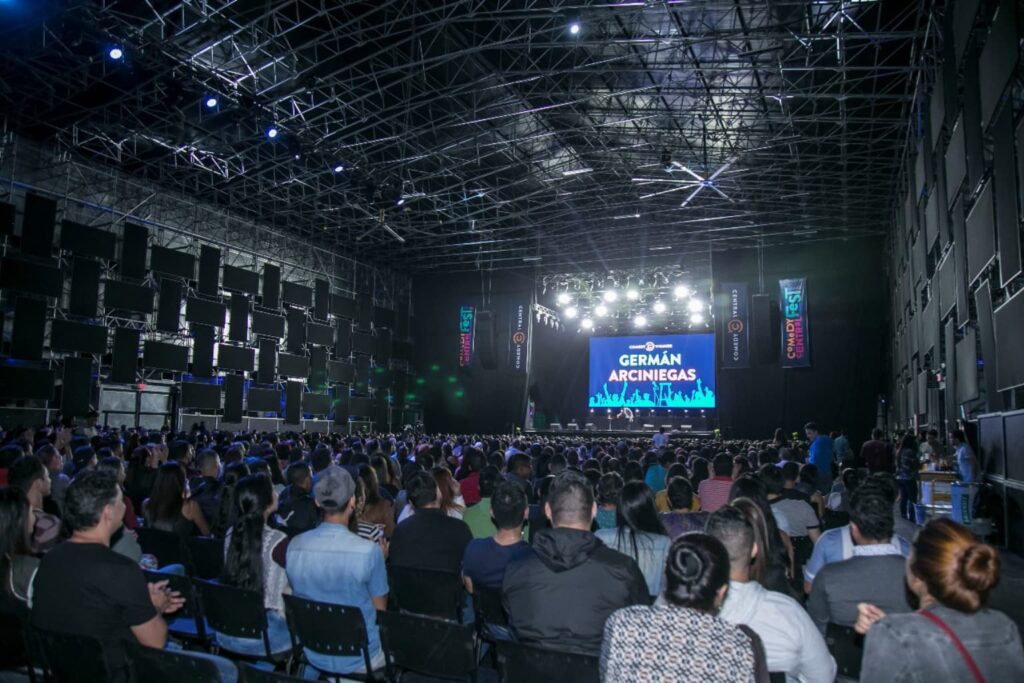 Fotografía de Germán Arciniegas en gran auditorio durante el Comedy Central Fest, con público masivo y escenario iluminado.