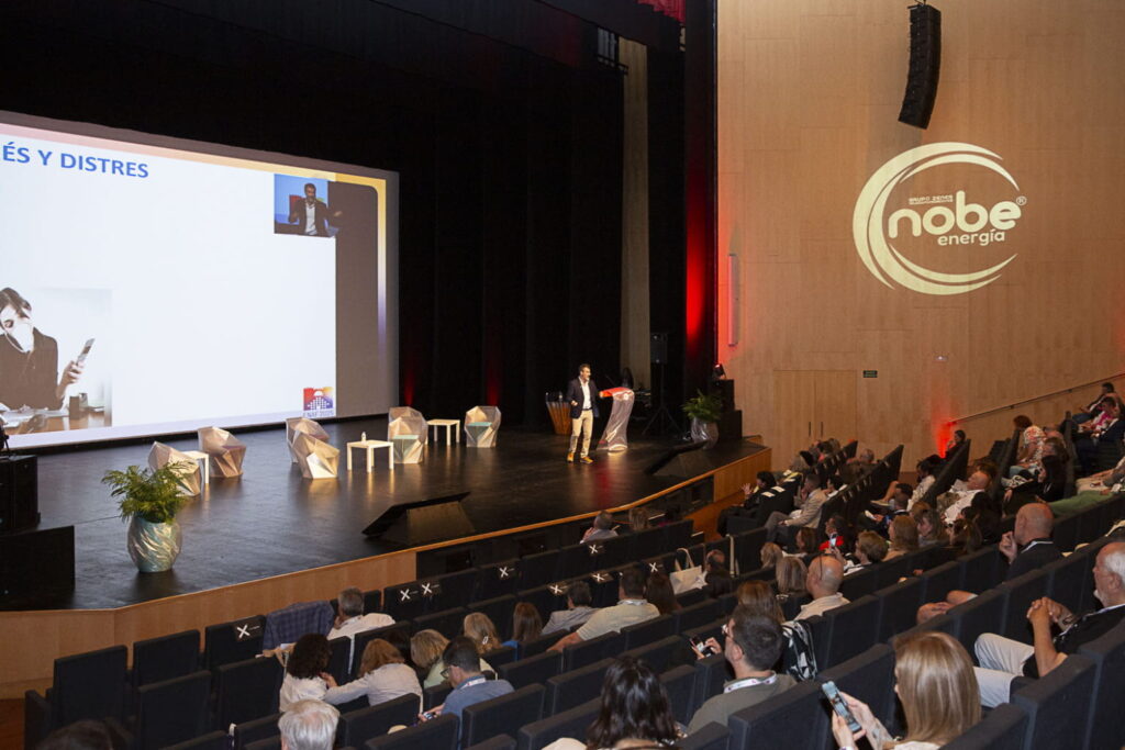 Fotografía de Zacarías Romero dando una conferencia en el auditorio de ENAF 2025, frente a un público numeroso, con una gran pantalla proyectando su presentación sobre gestión del estrés y distres.