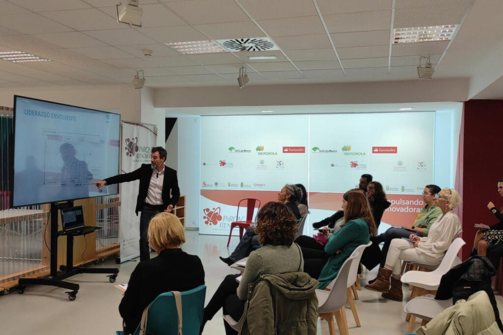 Fotografía de Zacarías Romero impartiendo una conferencia sobre “Liderazgo Envolvente” en el Parque Científico, señalando una pantalla mientras el público escucha atentamente.