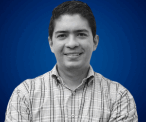 Marcos Burgos con camisa a cuadros y fondo azul.