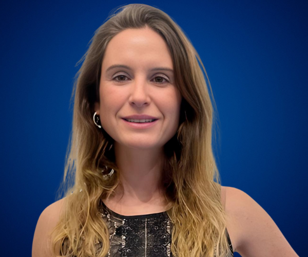 Fotografía de Carolina Pinto Grez, con fondo azul profesional, luciendo un vestido oscuro y expresión segura.