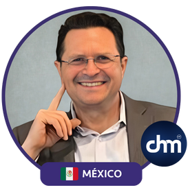 Fotografía de César Camacho, conferencista mexicano, sonriendo con actitud cercana y relajada, vistiendo saco gris claro y camisa blanca, enmarcado por el logotipo de CHM y la bandera de México.