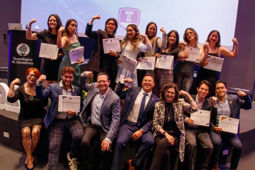 Fotografía grupal de César Camacho Montoya junto a estudiantes del Tecnológico de Monterrey posando con diplomas y gestos de fuerza en una ceremonia académica.