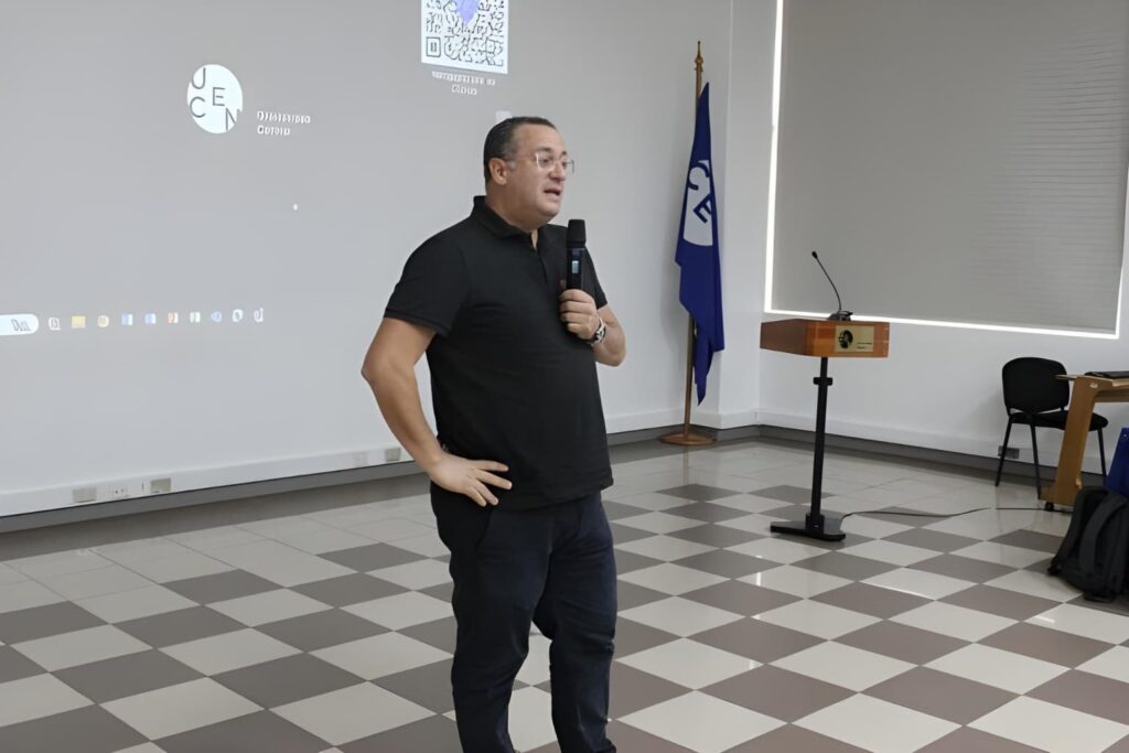 Fotografía de Felipe Peña y Lillo ofreciendo una conferencia en un auditorio universitario, sosteniendo un micrófono mientras comparte su mensaje.