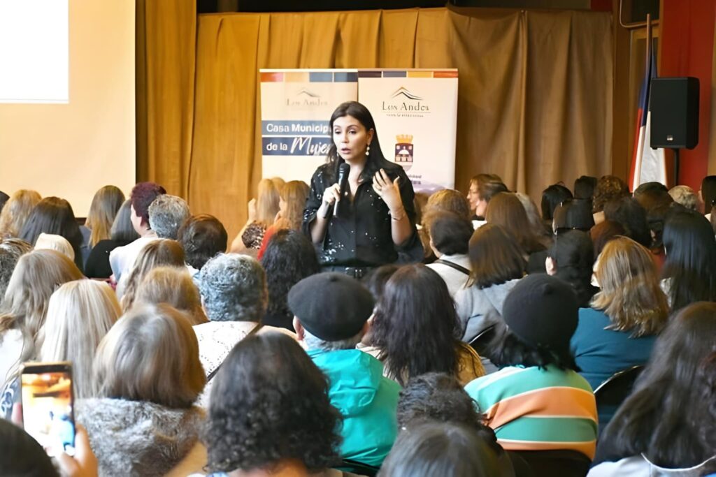 Fotografía de Pamela Lagos durante una conferencia en la Casa Municipal de la Mujer en Los Andes, Chile, hablando frente a un público mayoritariamente femenino.