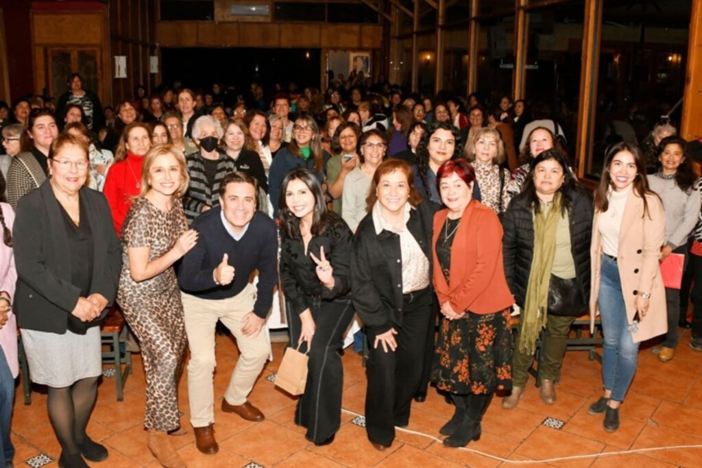 Fotografía de Pamela Lagos junto a un grupo de asistentes en un evento motivacional, todos sonriendo y mirando a cámara en un ambiente cálido e iluminado.