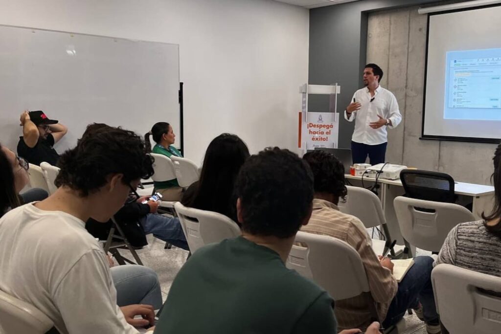 Fotografía de Patricio García impartiendo una charla motivacional a jóvenes en un salón académico, con la frase “