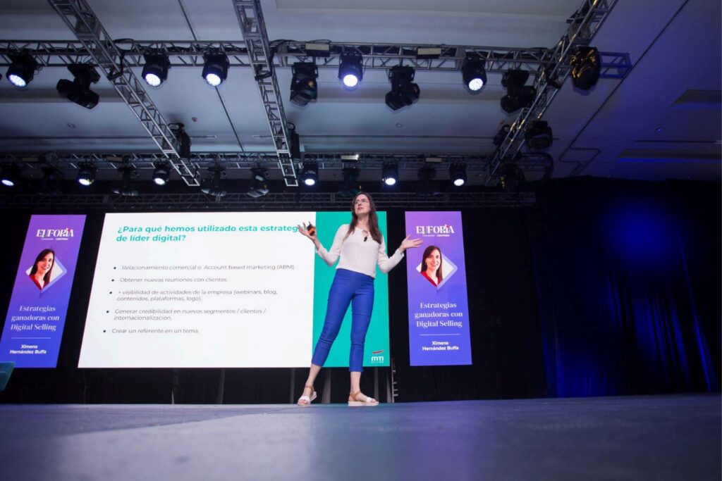 Fotografía de Ximena Hernández Buffa impartiendo una conferencia sobre estrategias ganadoras con Digital Selling en un gran auditorio, con pantallas que refuerzan su presentación.