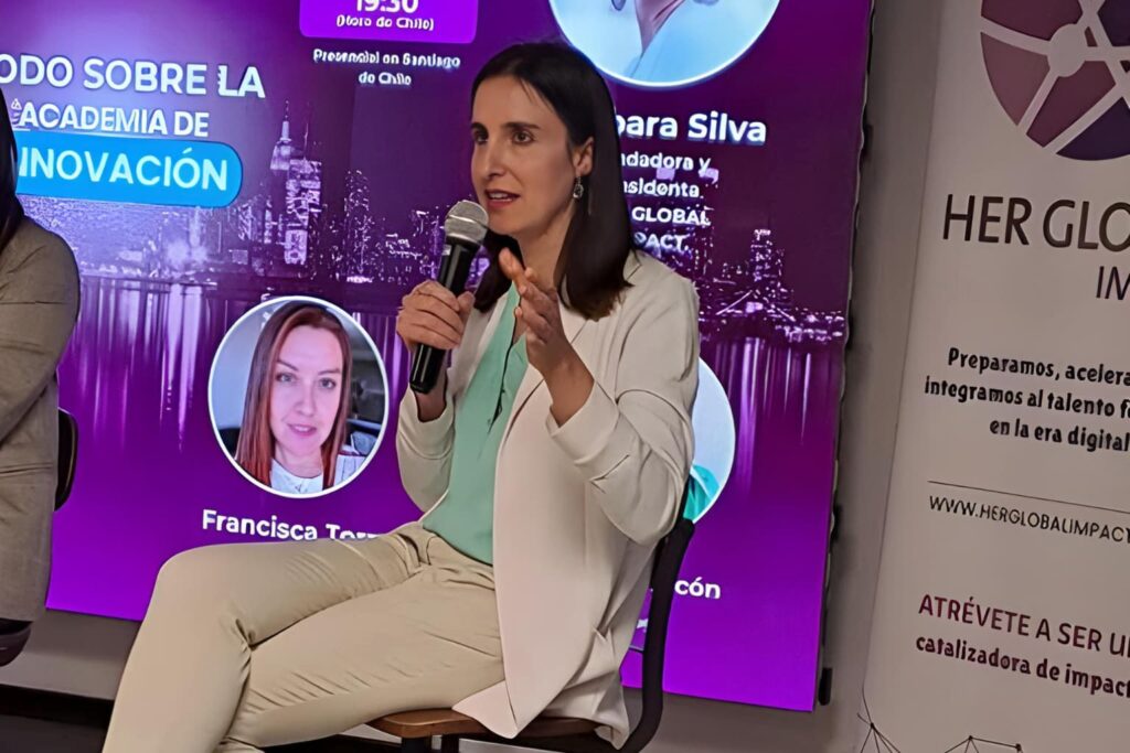 Fotografía de Ximena Hernández Buffa participando como panelista en un evento sobre innovación, sosteniendo un micrófono y compartiendo sus ideas frente a un fondo digital con información del encuentro.