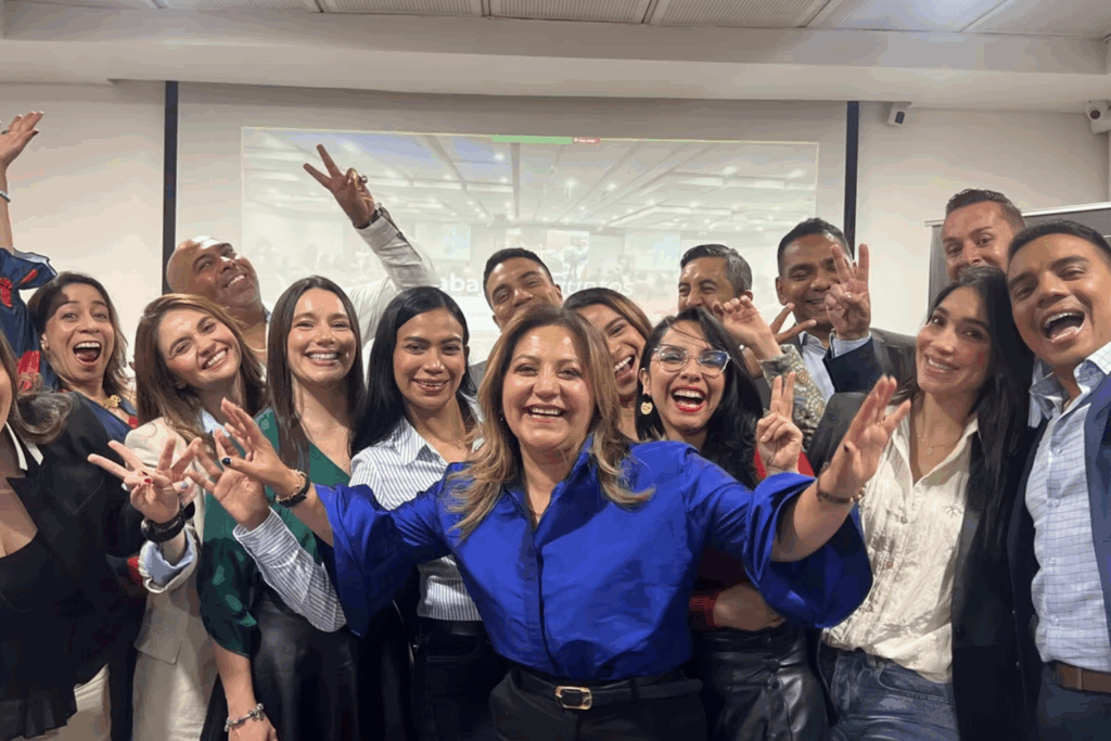 Fotografía de Liry Mantallana sonriendo junto a un grupo de personas en un ambiente de conferencia, todos mostrando entusiasmo y energía positiva.