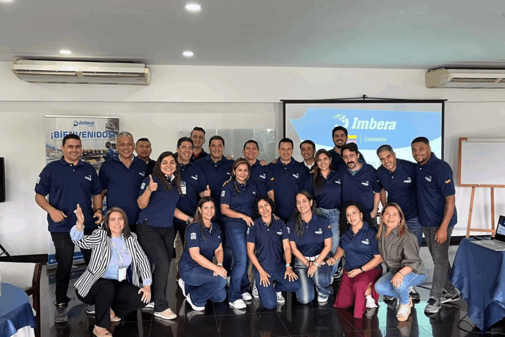Fotografía de Liry Matallana junto a un equipo corporativo de Imbera Colombia, todos vistiendo camisetas institucionales y sonriendo en una sala de capacitación.