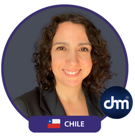 Fotografía de Paola Canessa, conferencista chilena, con cabello rizado corto y saco oscuro, sonriendo frente a un fondo gris con el logotipo de CHM.