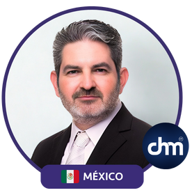 Fotografía de Pedro Eloy, conferencista mexicano, con traje formal oscuro, camisa blanca y corbata clara, posando frente a un fondo neutro con el logotipo de CHM.