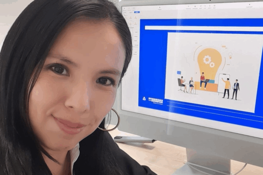 Fotografía de Erika Hernández sonriendo frente a una pantalla con una presentación digital sobre innovación y trabajo en equipo.