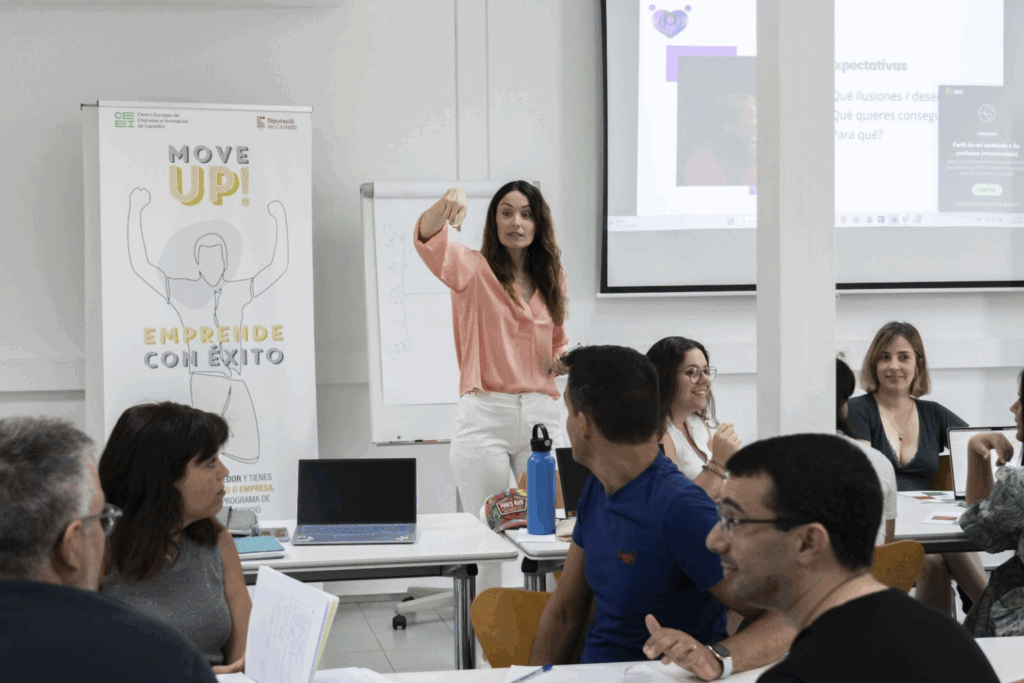 Fotografía de Eva Mazuecos liderando una dinámica participativa en una sesión del programa "Move Up!" del CEEI Castellón, señalando con fuerza mientras interactúa con un grupo de asistentes en un aula colaborativa.