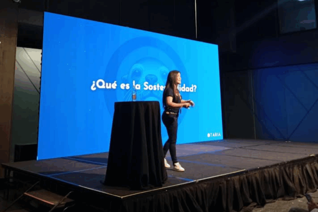 Simoné Oliva presentando una charla sobre sostenibilidad en escenario corporativo, promoviendo conciencia ambiental desde OTARIA.