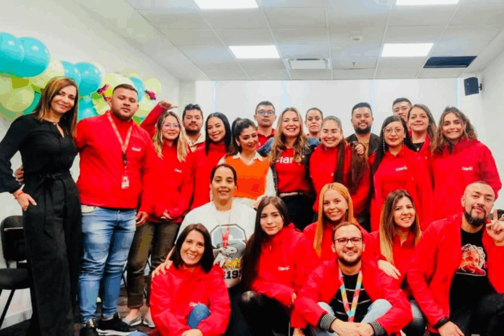Fotografía de Sonia Rojas junto a un equipo de colaboradores vestidos con chaquetas rojas de Claro, en un ambiente corporativo decorado con globos, transmitiendo energía positiva y trabajo en equipo.