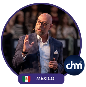 Fotografía de Sal Barrena durante una conferencia en México, vestido con traje formal y camisa blanca, hablando frente a una audiencia atenta en un entorno profesional e iluminado.