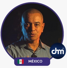 Fotografía de Julian Aguilar Estrada, con expresión seria y micrófono de solapa, iluminado con tonos cálidos sobre fondo oscuro, acompañado del distintivo de México y el logotipo de CHM.