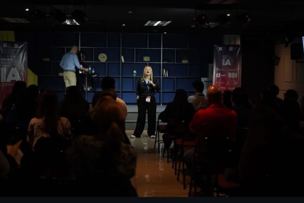 Fotografía de Nancy Reeves en una sala de conferencias con iluminación tenue, hablando frente a un público atento, con fondo azul y banners del Congreso CNEP.