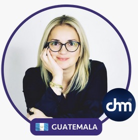 Fotografía de Nancy Reeves, mujer rubia con gafas negras, sonriendo levemente sobre fondo blanco, enmarcada con borde circular morado, bandera de Guatemala y logotipo de "CHM".
