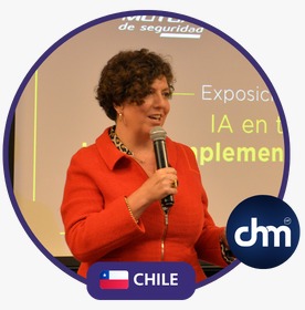 Fotografía de Jennyfer Salvo durante una exposición, sosteniendo un micrófono y hablando con seguridad frente a una pantalla proyectada, con distintivo de Chile y logo de CHM.