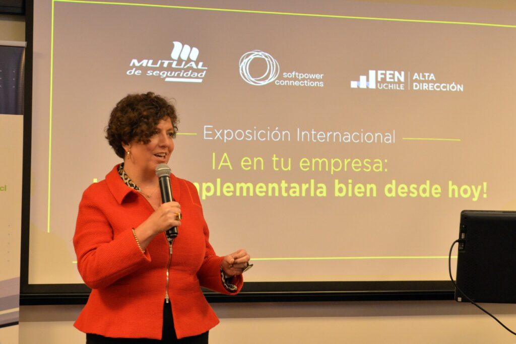 Fotografía de Jennyfer Salvo exponiendo con micrófono en mano frente a una pantalla con la temática "IA en tu empresa: Implementarla bien desde hoy", durante un evento profesional.